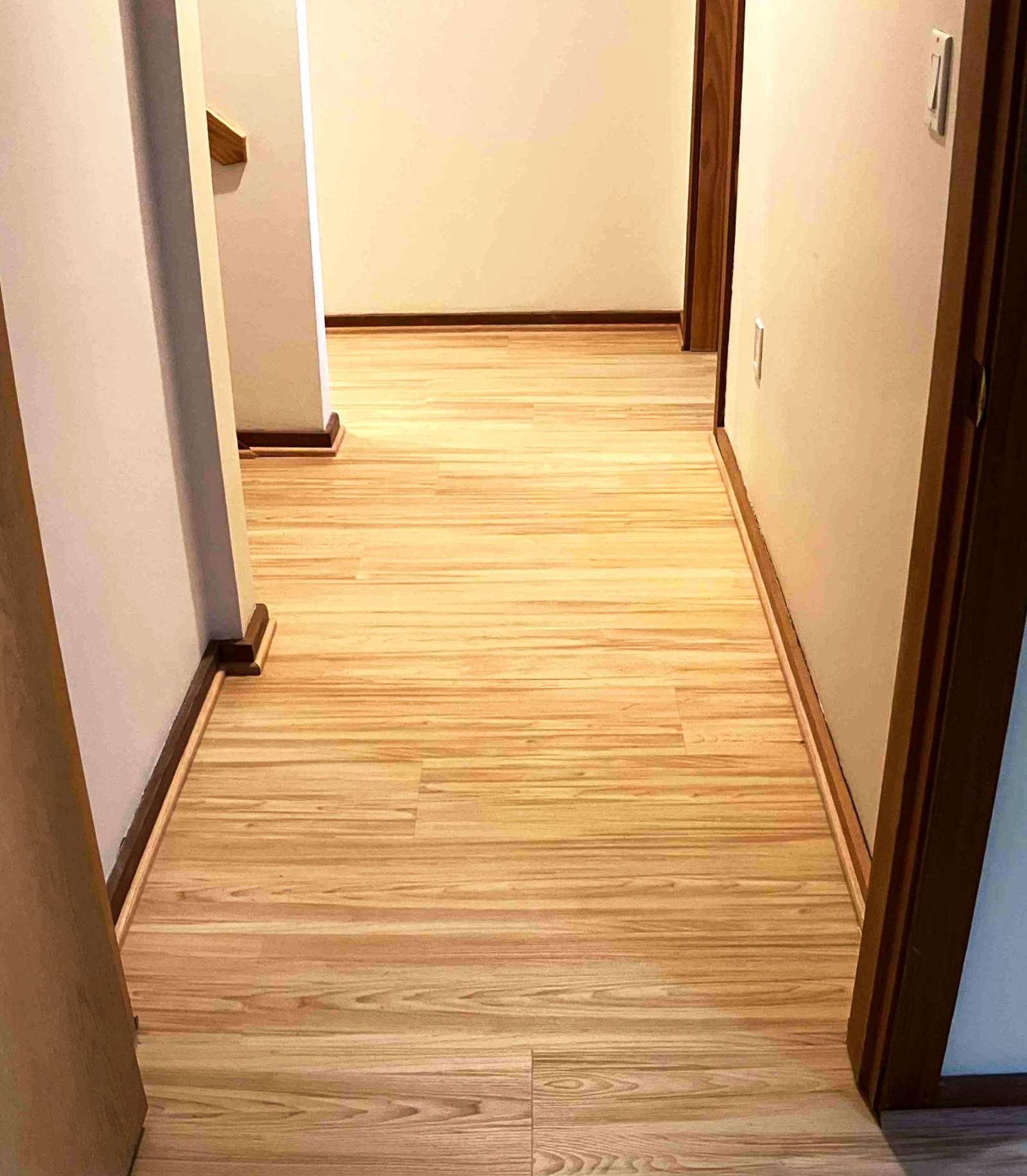 New LVP flooring with oak transitions and shoe molding in a hallway